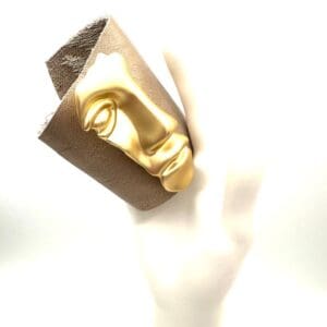 Golden face sculpture on textured surface.